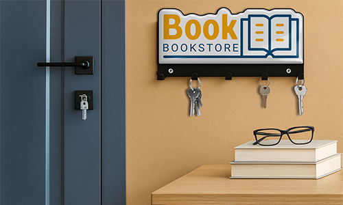 Wall key holder with Book BOOKSTORE logo and open book graphic, keys hanging, books and glasses on wooden surface