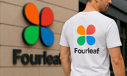 Mand iført personlig hvid T-shirt med farverigt “Fourleaf” logo der matcher branding på bygningens væg i baggrunden.