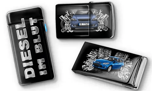 Drei schwarze Feuerzeuge mit Auto-Motiven und metallischen Akzenten. Eines trägt den Text „DIESEL IM BLUT“, die anderen zeigen rote und blaue Autos mit mechanischen Motiven. Ein sportlicher Ton wird vermittelt.