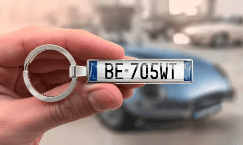 Silver license plate keychain shows personalized numbers while held in hand