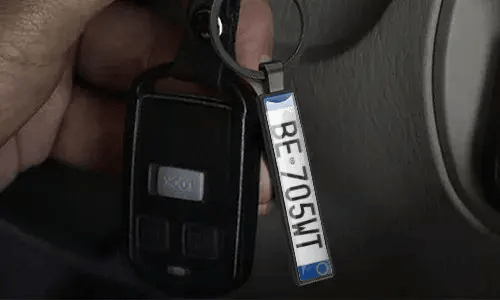 Llavero plateado de placa de matrícula cuelga de las llaves del coche dentro del vehículo