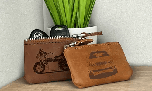 Two brown leather key pouches with zippers: one with motorcycle and plate 