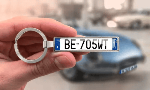 Portachiavi con targa personalizzata, tenuto in mano con auto sullo sfondo