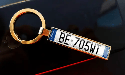 Nyckelring med registreringsskylt fäst vid nycklar i fickan, med bil i bakgrunden