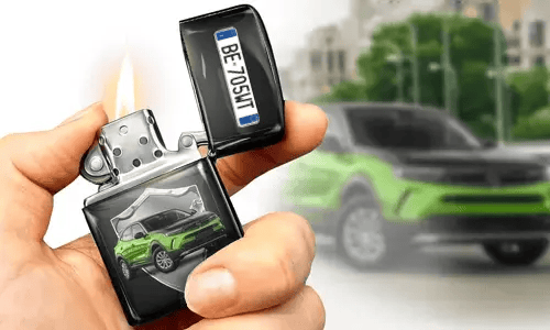 A hand holds a lit lighter with a green car image and license plate on it. A blurred green car is in the background, matching the lighter's design.