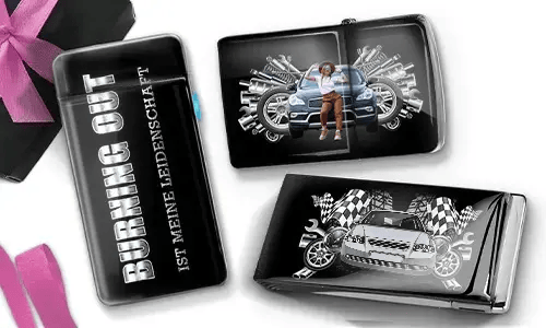 Drei schwarze Geldbörsen mit Auto-Designs. Eine trägt die Aufschrift „Burning Out ist meine Leidenschaft“, eine andere zeigt ein Auto mit Kolben und einer Person, und die dritte zeigt ein Auto mit karierten Flaggen und Kolben. In der Ecke liegt eine violette Schleife.