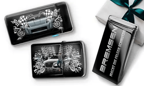 Car-themed wallets featuring sleek cars, checkered flags, and tire patterns on a black background. Beside them, a black gift box with silver text.