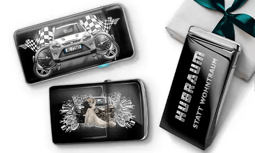 Three black wallets with car-themed designs and checkered flags, set against a white background. One shows a car with wheels, another features a couple, and one has 