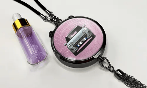 Pendant with pink background and white sports car, next to purple dropper bottle with gold cap