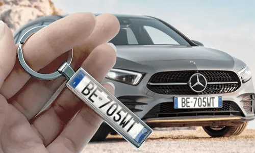 Llavero estilo placa de matrícula cómic, sostenido en la mano con la placa de coche correspondiente en el fondo