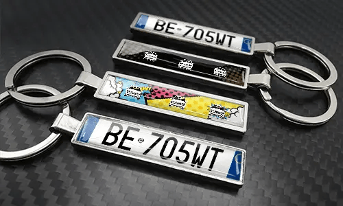 Comic-style license plate keychains arranged on a carbon-textured surface with colorful car graphics