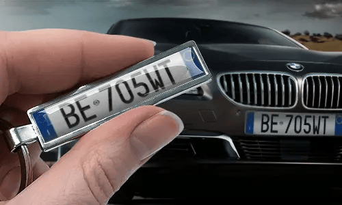 Comic license plate keychain with custom number held in hand near matching car plate