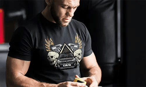 Black T-shirt with graphic of car, skulls, pistols, golden wings, and starry triangle background