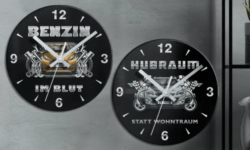 Two black wall clocks with car illustrations and German text: BENZIN IM BLUT and HUBRAUM STATT WOHNTRAUM