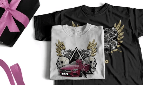 Two T-shirts, one white with red car, skulls, wings; one black with mechanical skulls, gift box nearby