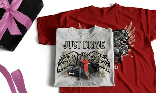 Two T-shirts with bold graphics, one white with JUST DRIVE and couple near car, one red with winged engine and flames, next to gift box with pink ribbon
