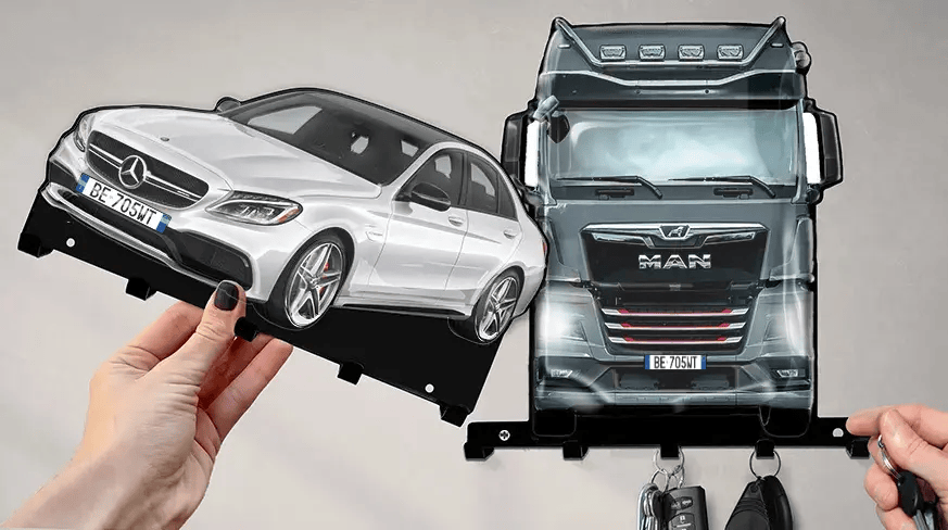 Wandmontierter Schlüsselhalter mit abnehmbaren Formen eines weißen Mercedes-Benz und eines schwarzen MAN-LKWs, jeweils mit Haken für Schlüssel